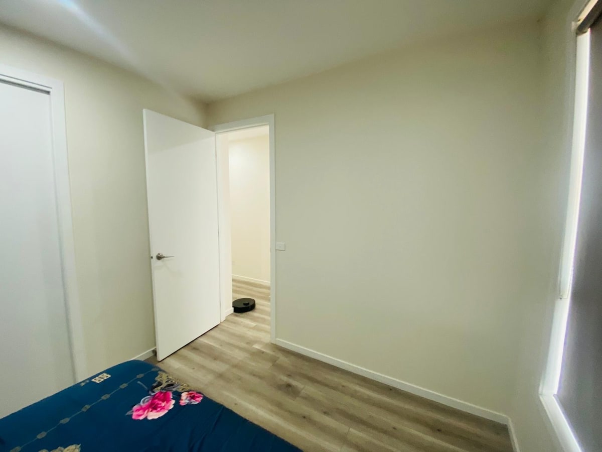 Bedroom with navy floral quilt and open doorway at Luxe Nest, 33 Maya Avenue